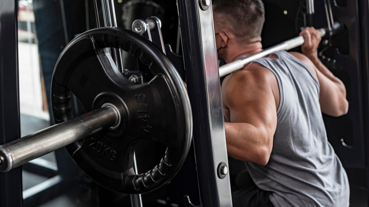 A person performs a Smith machine back squat.