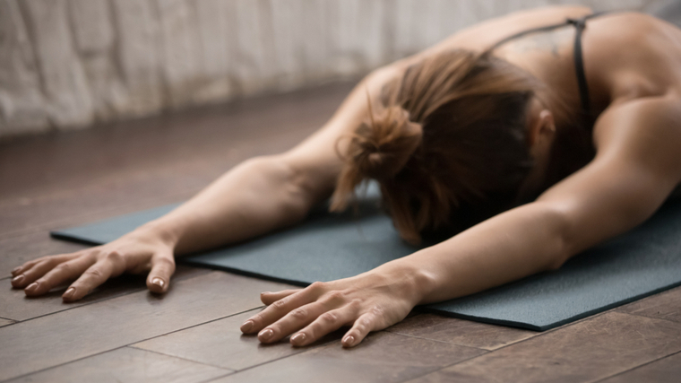 woman lying on mat with arms out 