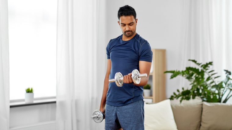 A person performs dumbbell curls at home.