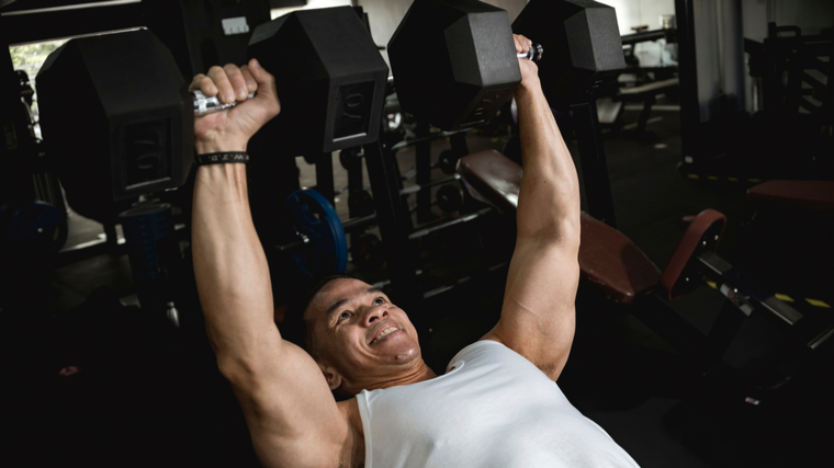 A person completes an incline dumbbell bench press rep.