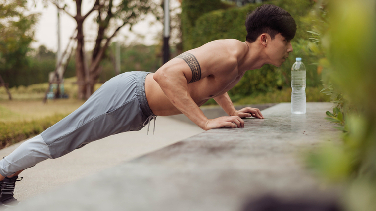 A person performs incline pushups outside.