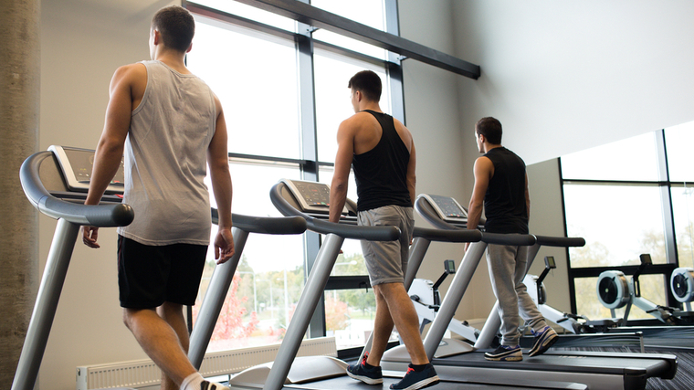 Three people walk on adjacent treadmills.