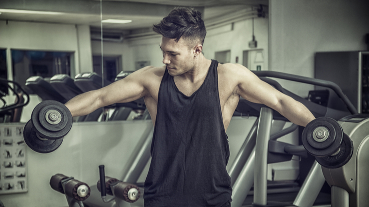 A person works with dumbbells in the gym.