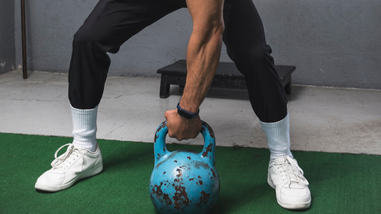 A person picks up a kettlebell.