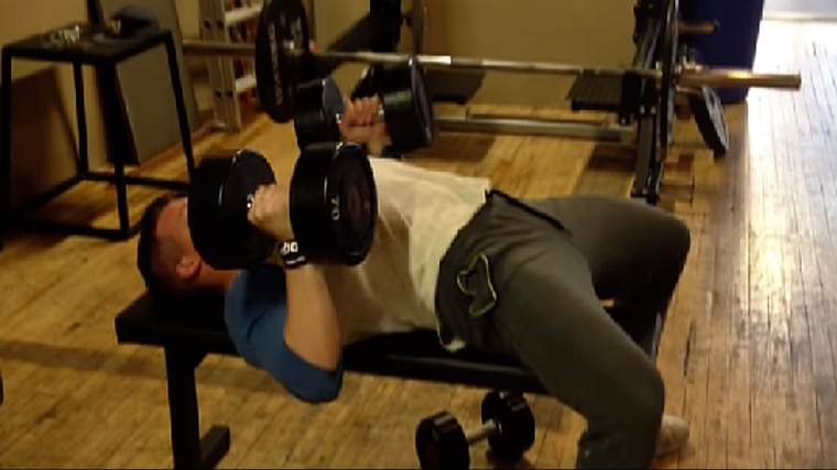 A person lowers dumbbells toward his chest with a neutral grip.