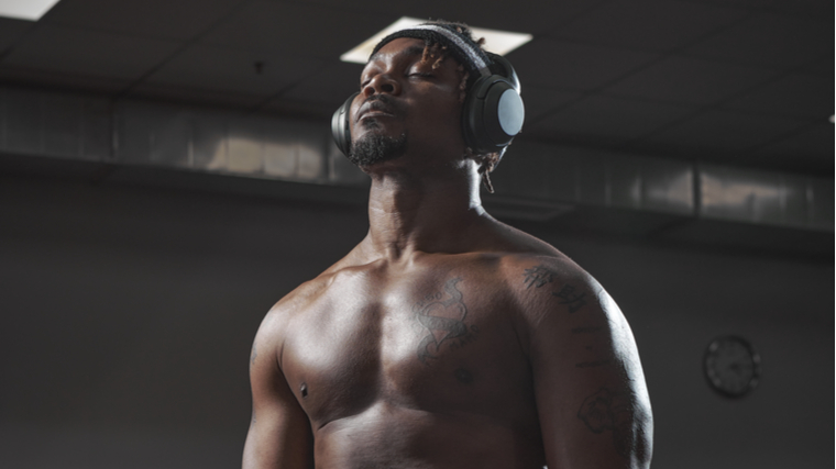 A person closes his eyes while listening to music in the gym.