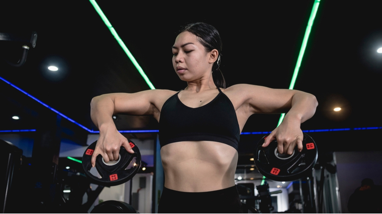 A person raises two small weight plates in the gym.