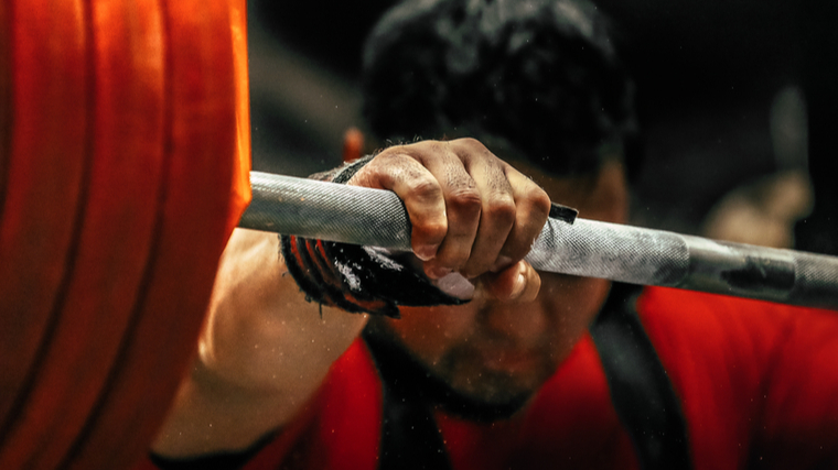 A close-up of someone's hand on a barbell as they prepare to squat heavy.