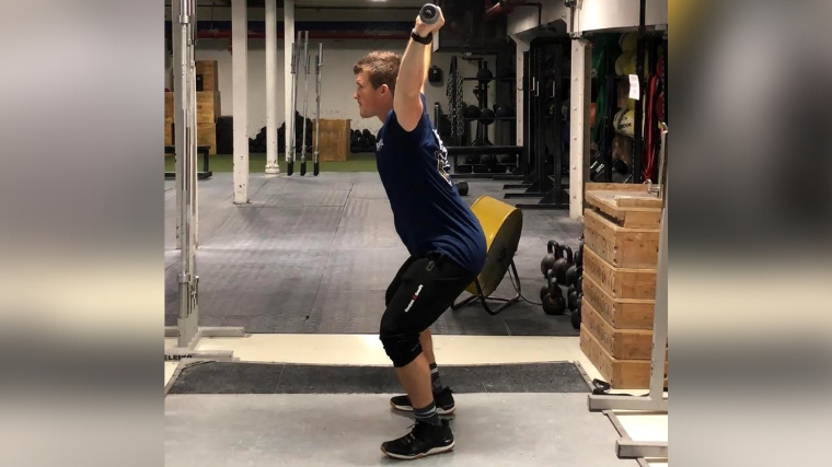 A person ascending from an overhead squat position.