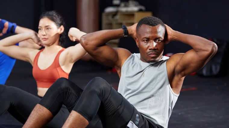 two athletes perform sit-ups in gym