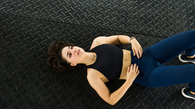 woman rests on gym floor between sit-ups