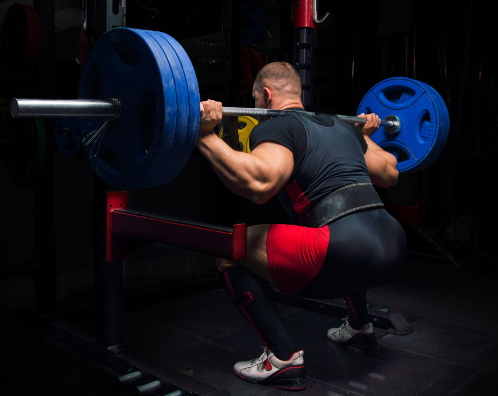 Powerlifter performing a squat while using a weight belt