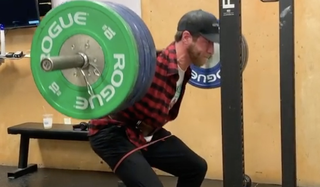 Barbell squats with 2025 bands around thighs