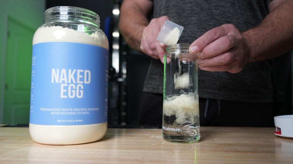 Our tester mixes a scoop of Naked Egg into a clear glass of water.