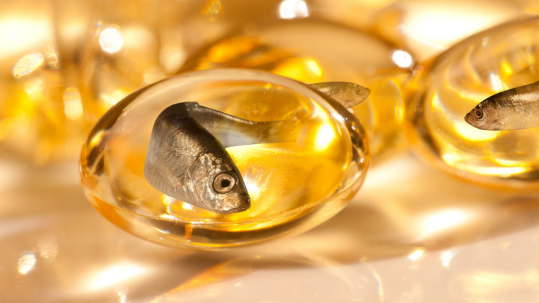 golden fish oil pills with little fish inside of them swimming