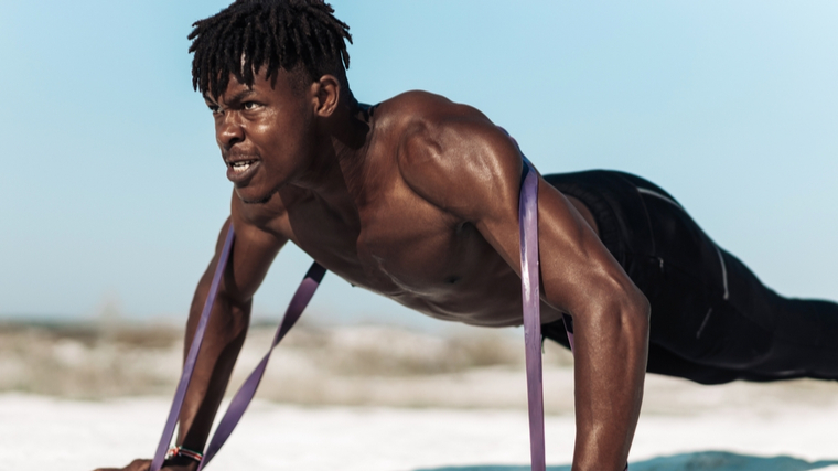 A person performs a banded push-up outside.