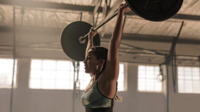 woman pressing barbell overhead