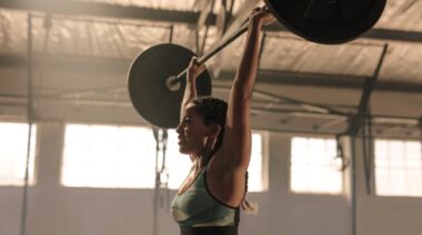 A person working out with a barbell overhead.