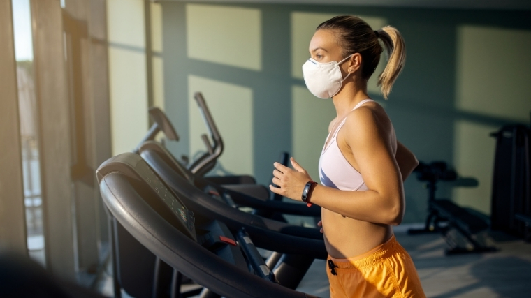 Woman wearing mask running on treadmill