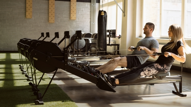 Man and woman rowing on erg