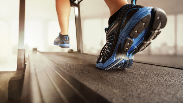 Person running on treadmill incline with blue and black shoes