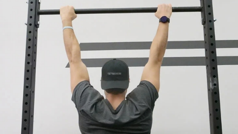 Attractive muscular woman, holding on pull ups bar, back view