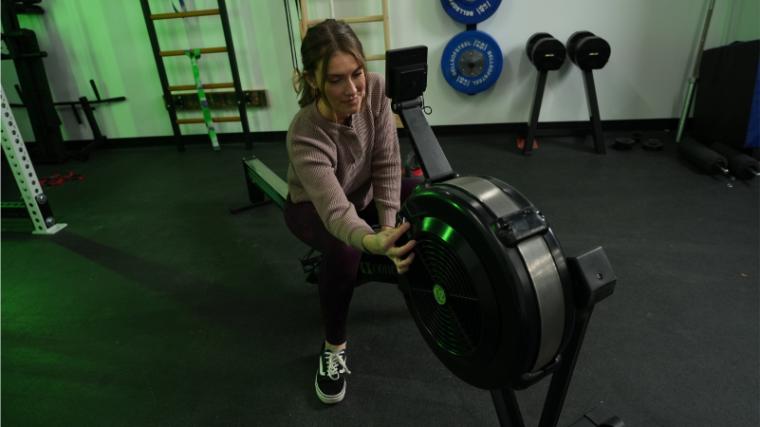 A BarBend tester adjusting the resistance on the Concept2 RowErg.