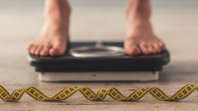 Person stepping on scale to track weight gain