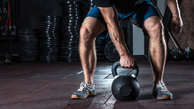 man grabbing kettlebell with one hand 