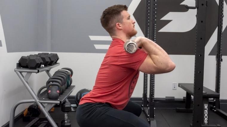 man squatting a barbell holding it in a front rack position