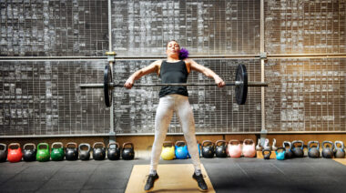 A person performs a snatch in a gym.