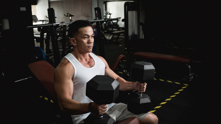 A person sits on an adjustable bench and prepares to lift heavy dumbbells.