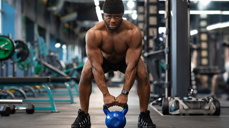 A person prepares to lift a kettlebell in the gym.