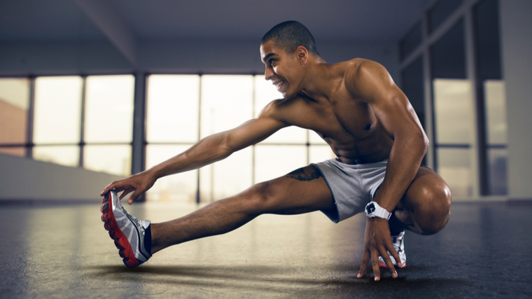 A person stretches their hamstring with a deep lateral lunge.