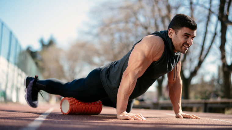 man foam rolling on track 