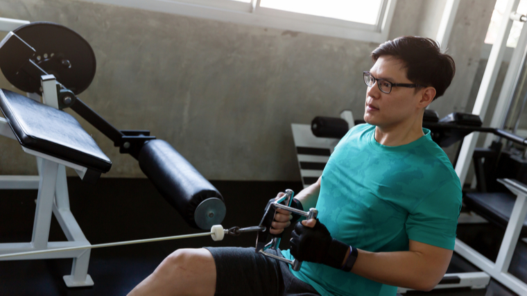 A person performs a seated cable row in the gym.