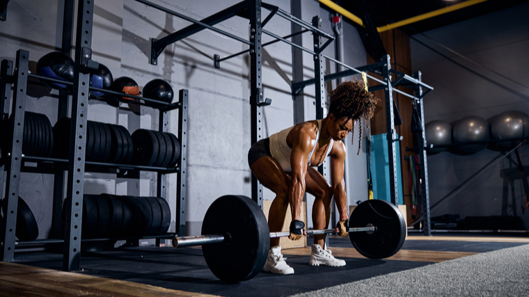 A person performs a deadlift in the gym.