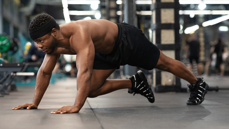 A person performs a mountain climber in the gym.