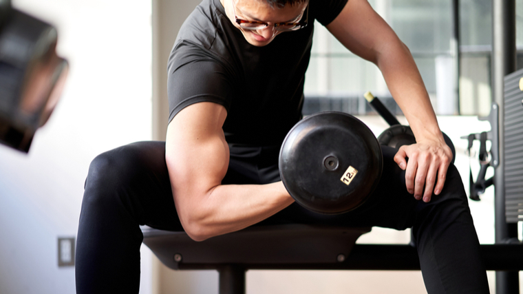 A person performs concentration curls in the gym.