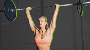A person doing shoulder exercises with a barbell for stability and aesthetics.