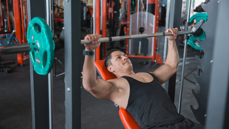 A person performs an incline press in the Smith machine.