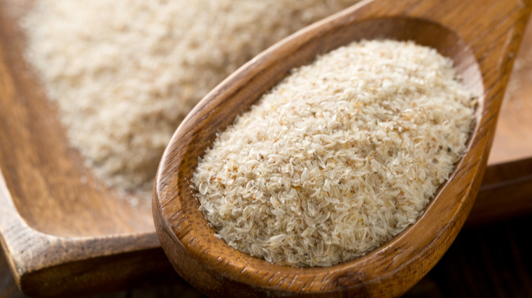 A wooden spoon holds a heap psyllium husk.