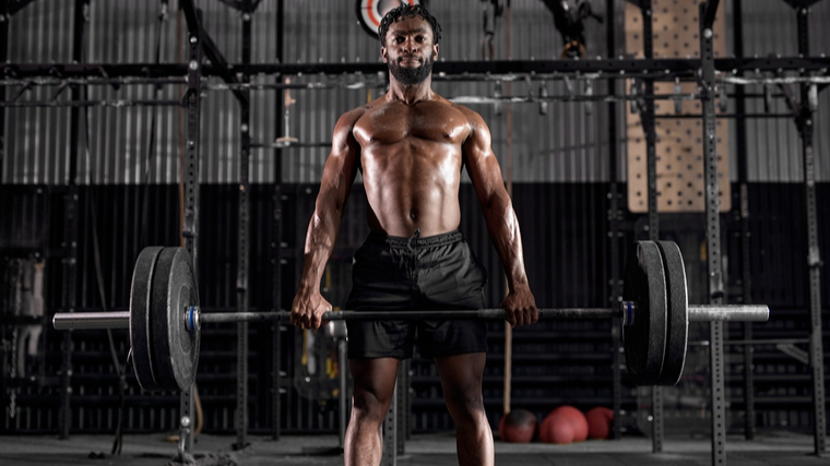 A person locks out a deadlift in the gym.