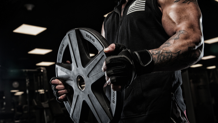 A close-up shot shows a person holding a weight plate in their hands.