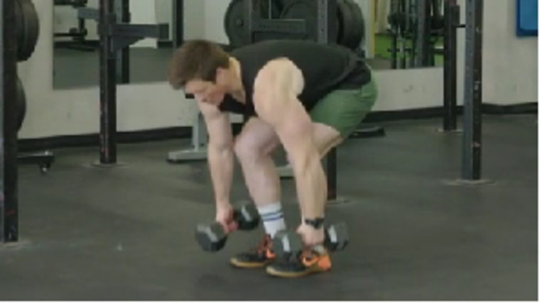 A person prepares to perform a dumbbell clean & press.