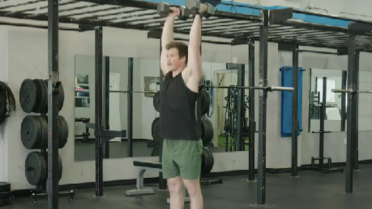 A person performs a dumbbell clean & press.