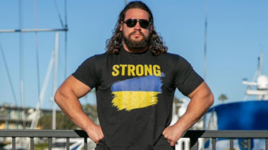 Martins Licis stands wearing a shirt that says "strong" with the colors of the Ukranian flag.