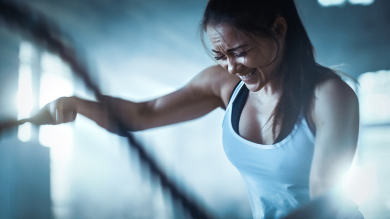 A person exerts a lot of effort performing battle rope waves.