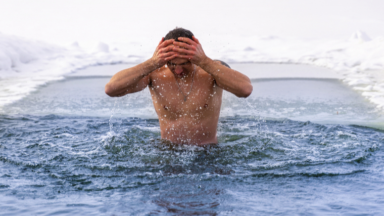 A person emerges from icy water.