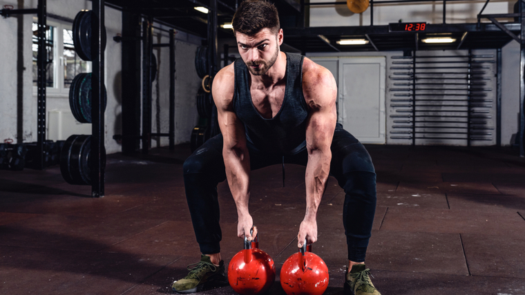 A person prepares to perform a double kettlebell swing.